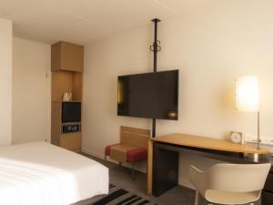 a hotel room with a bed and a desk and a tv at Novotel Antwerpen - Ekeren in Antwerp