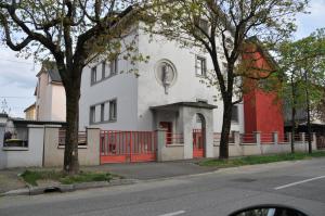 a white building with red doors on a street at Atrium flat in the Villa in Ljubljana