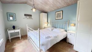 ein Schlafzimmer mit einem weißen Bett und zwei Nachttischen in der Unterkunft Dans le centre du village d'ARS EN RE, charmante villa bien décorée in Ars-en-Ré