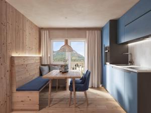 a kitchen with a wooden table and a blue chair at DORFSTUDIO Apartments in Söll