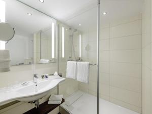 een witte badkamer met een wastafel en een douche bij Mercure Hotel Berlin City West in Berlijn