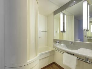 een badkamer met een bad, een wastafel en een spiegel bij Mercure Hotel Berlin City West in Berlijn