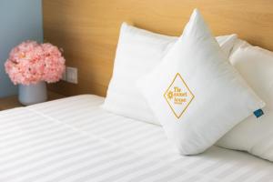 een bed met witte kussens en een vaas met bloemen bij Lotus Home Cafe in Phu Quoc