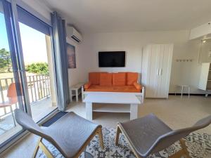 ein Wohnzimmer mit einem orangenen Sofa und 2 Stühlen in der Unterkunft STUDIO Terrasse Plage CLIM WIFI Park in Palavas-les-Flots