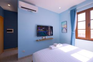 een blauwe slaapkamer met een bed en een tv aan de muur bij Lotus Home Cafe in Phu Quoc +84 foto's