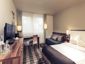 a hotel room with a bed and a desk at Mercure Hotel Saarbrücken Süd in Saarbrücken