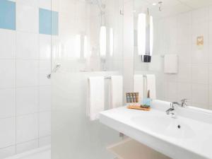 Un baño blanco con lavabo y ducha. en Novotel Warszawa Airport, en Varsovia
