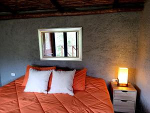 ein Schlafzimmer mit einem orangefarbenen Bett mit einem Fenster in der Unterkunft Mama Anzas house in a magical mountain in Villabol