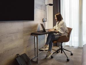 a woman sitting at a desk with a laptop at Novotel Lausanne Bussigny in Lausanne