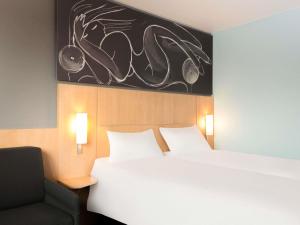a hotel room with a bed and a chair at ibis 3 Lacs Neuchâtel in Thielle-Wavre