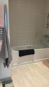 y baño con bañera y toalla negra. en Spacious ensuite room in front of station, en Ilford