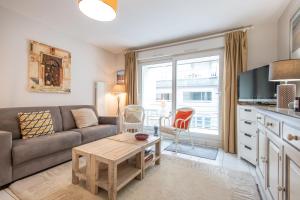 a living room with a couch and a table at Les Oyats - Parking - Balcon - Plage in Le Touquet-Paris-Plage +11 photos