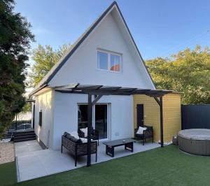 a white house with a roof with two chairs and a table at Nyárfás Panoráma Vendégház in Dunavarsány