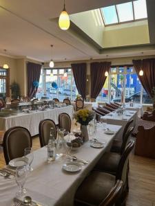 uma sala de jantar com mesas e cadeiras com copos e flores em Alcock & Brown Hotel em Clifden mais 18 fotografias