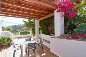 a patio with a table and chairs and flowers at Cortijo A Navas in Frigiliana