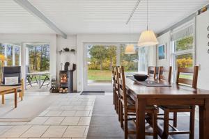 a dining room with a table and chairs and a fireplace at Well-Designed House In Scenic Surroundings in Martofte