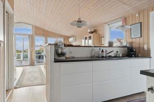 a kitchen with white cabinets and a large window at Active Coastal Holiday In Cozy Cottage in Strandlyst