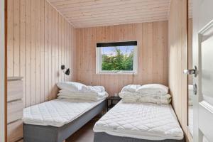 two beds in a room with a window at Active Coastal Holiday In Cozy Cottage in Strandlyst