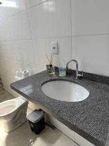 a bathroom with a sink and a toilet at Casa LF com suíte e garagem coberta in Mineiros