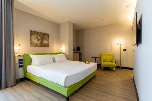 a hotel room with a bed and a yellow chair at H2C Hotel Milanofiori in Assago +108 photos