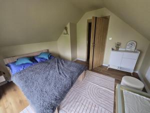 a bedroom with a bed with blue pillows and a rug at Domek pod Skrzycznym in Kalna +2 photos