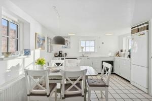 een witte keuken met een witte tafel en stoelen bij Family-Friendly Beachside Holiday Home in Arnager