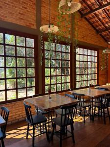 two tables and chairs in a room with windows at Pousada Flor do Café in Ubajara