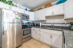 a kitchen with white cabinets and a stainless steel refrigerator at Perfect Ocean View - Oceanfront Condo, Private Balcony, Community Pool in Kill Devil Hills