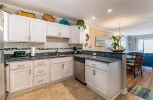a kitchen with white cabinets and a dining room at Perfect Ocean View - Oceanfront Condo, Private Balcony, Community Pool in Kill Devil Hills