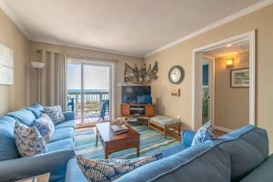 Una sala de estar con un sofá azul y un televisor en Perfect Ocean View - The Sands - K0003A, en Croatan Shores