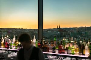 Un hombre parado frente a un estante de botellas en Hilton Prague Hotel, en Praga