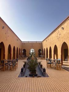 a courtyard with a fountain and tables and chairs at Hotel Berber Palace Merzouga in Hassilabied