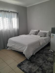 a bedroom with a bed with white sheets and a window at Shalom Villa Guesthouse Walvis in Walvis Bay