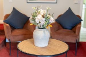 a vase of flowers sitting on a table with two chairs at Sunnyholme - New! Yorkshire Luxurious Cottage in Hawes
