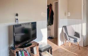 a living room with a flat screen tv and a chair at 3 Bedroom Lovely Home In Skibby in Rønø