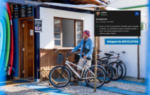 a woman standing next to two bikes in front of a sign at Cosmopolitans Hostel in Ubatuba