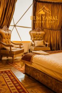 ワディ・ラムにあるRUM YANAL lUXURY CAMPのベッドと椅子2脚と窓のある寝室