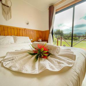 a white bed with a bouquet of flowers on it at Cabañas Rimü - Cabañas para 8 personas in Futrono