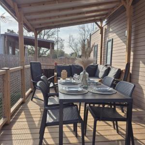 eine Terrasse mit einem Tisch, Stühlen und einem Sofa in der Unterkunft Le Cocon Mobil Home à 150 m de la plage Camping 5 Etoiles Parc Aquatique in Torreilles