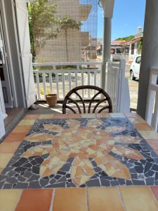 Una mesa y una silla en un porche con suelo de mosaico. en Logement « Alpinia », en Capesterre 7 fotos más