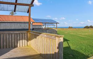 a wooden fence and a building with a field and the ocean at Pet Friendly Home In Hanstholm With Private Swimming Pool, Can Be Inside Or Outside in Pugdal +21 photos