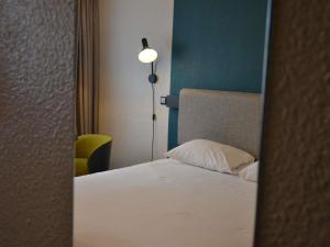 a bedroom with a bed with a lamp and a pillow at ibis Chambery in Chambéry