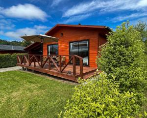 a small cabin with a deck with an umbrella at Cabañas Rimü - Cabañas para 8 personas in Futrono