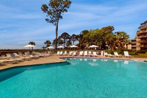 ヒルトン・ヘッド・アイランドにあるOcean One 215のラウンジチェアとパラソル付きの大型スイミングプール