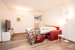 a bedroom with a bed and a red chair at La Casa di Paola in La Thuile