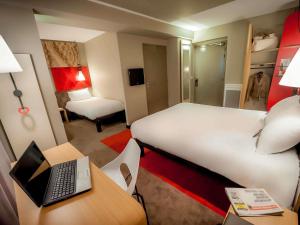 a hotel room with a bed and a desk with a laptop at ibis Quimper in Quimper