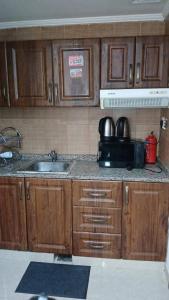 eine Küche mit Holzschränken, Spüle und Mikrowelle in der Unterkunft Daily Basis Furnished rooms Deira in Dubai
