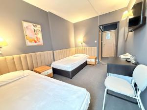 a room with two beds and a desk and a chair at Struma Hotel in Pernik