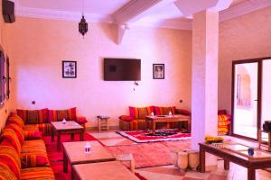 a living room with red couches and a flat screen tv at Hotel Berber Palace Merzouga in Hassilabied