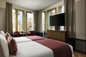 a hotel room with a bed and a flat screen tv at Tivoli President Milano Hotel in Milan